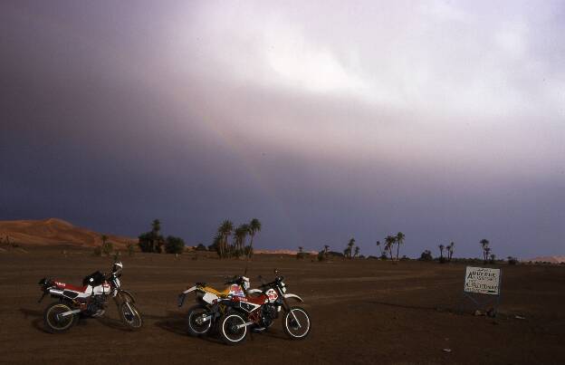 Regenbogen und in der Ferne Dünen. Wir fahren im Nieselregen Richtung Erg Chebbi. Leuchtende Dünen und ein Regenbogen zeigen die Richtung an.